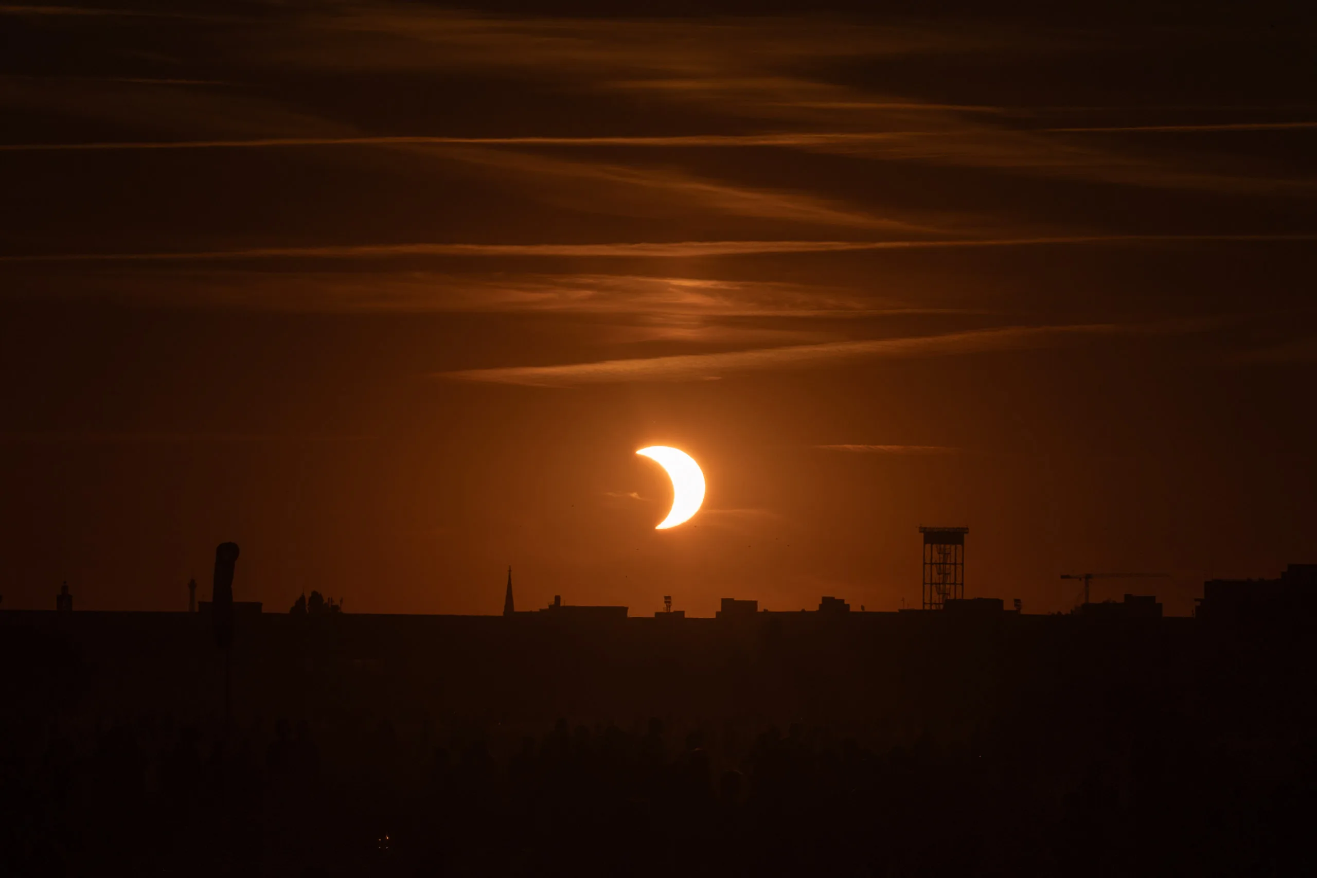 Photographing the Solar Eclipse in Berlin Fedor Vasilev Photographer In Berlin Partial solar eclipse appearing over a dark city skyline at sunset, captured by Berlin-based photographer Fedor Vasilev.