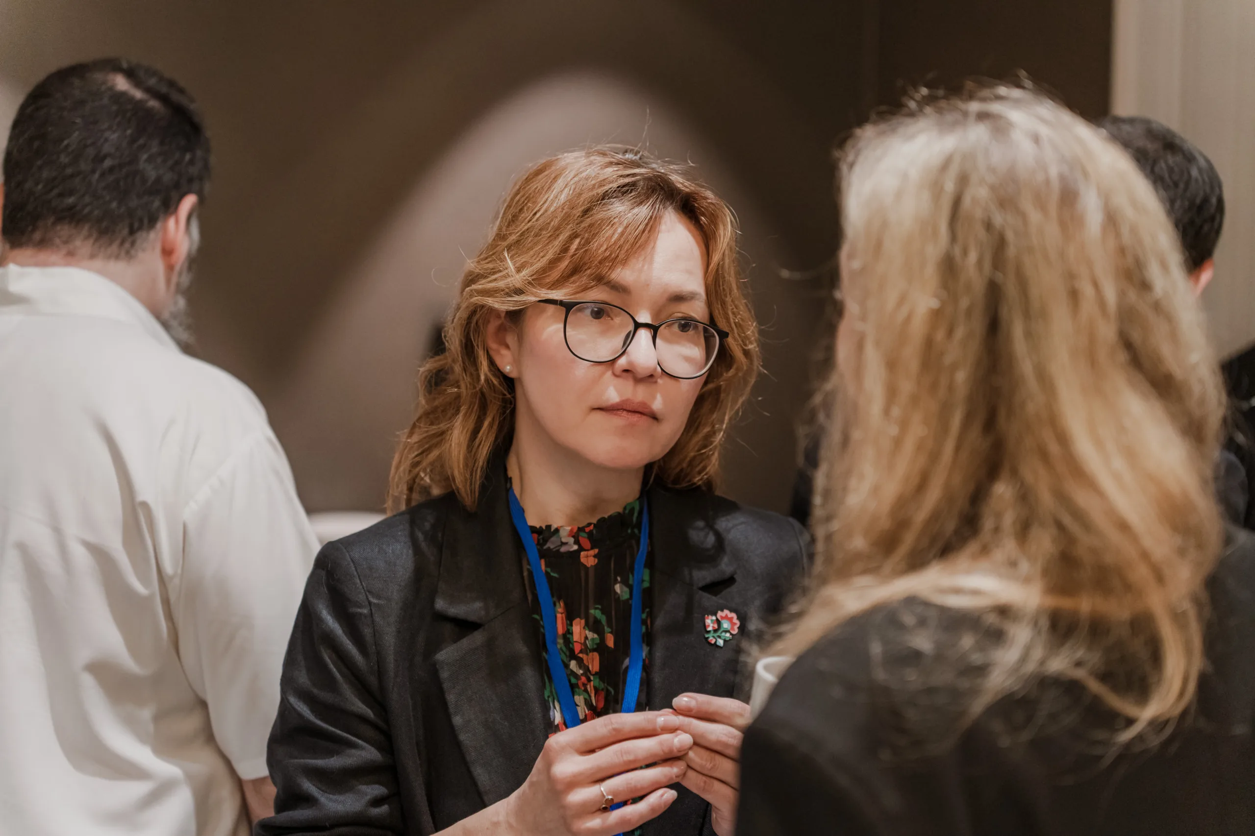 EU4Energy Conference Photography in Vienna Fedor Vasilev Photographer In Berlin Glasses-wearing woman with a floral top and black blazer listens to a colleague during a coffee break.