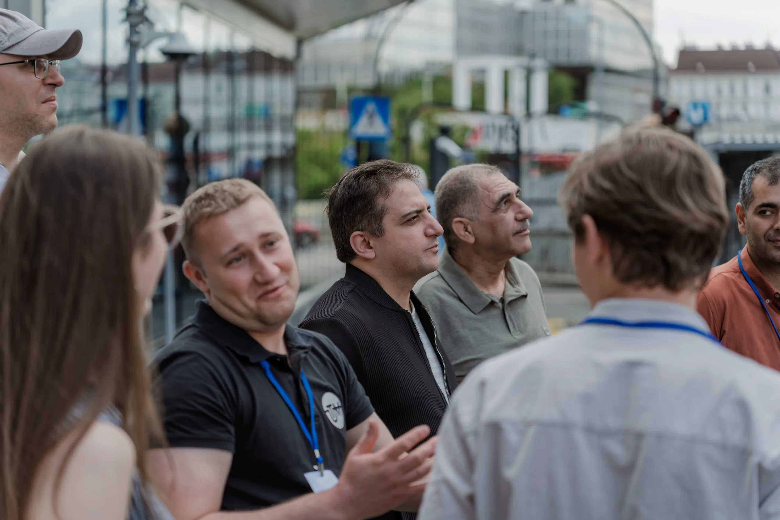 EU4Energy Conference Photography in Vienna Fedor Vasilev Photographer In Berlin Diverse group of conference attendees wearing blue lanyards gather outdoors for an informal conversation.