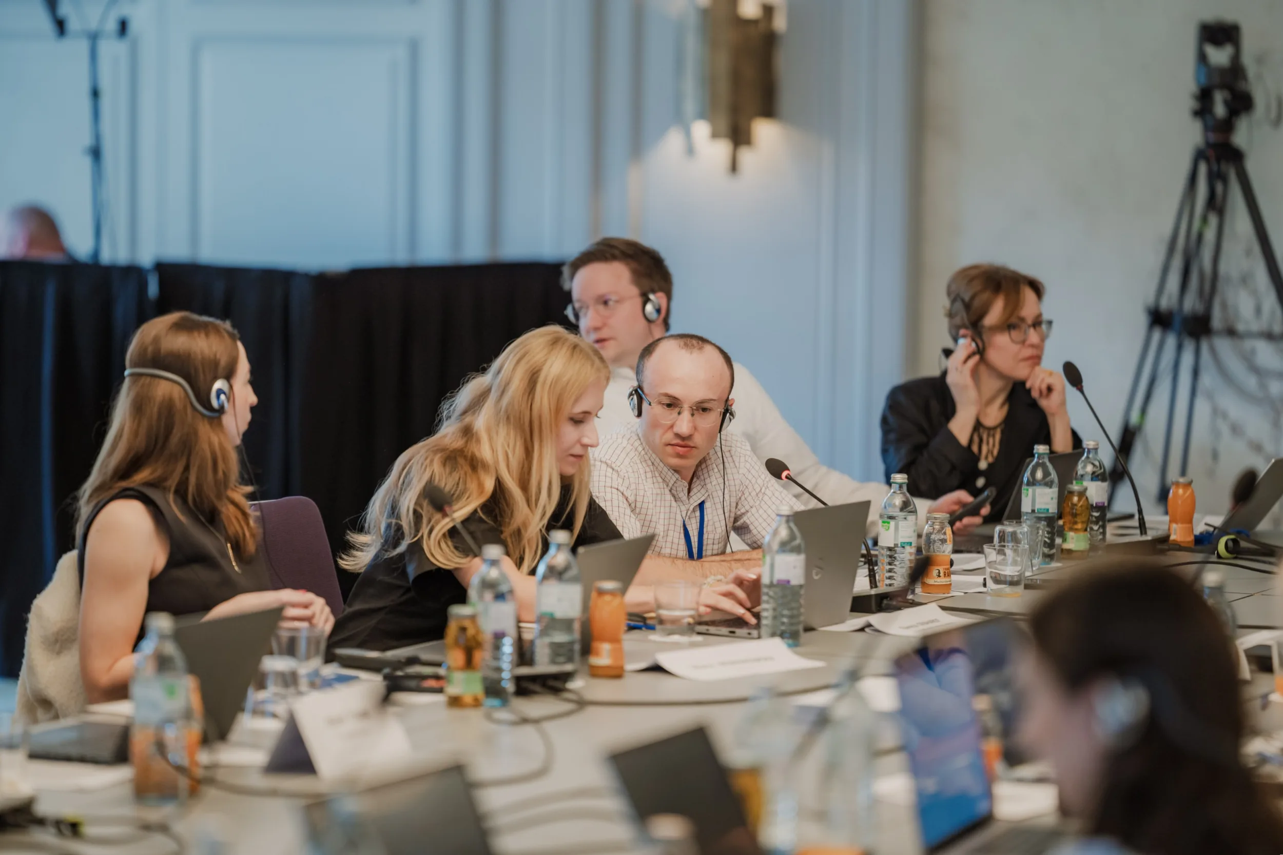 Same-Day Event Photography: How I Deliver Conference Photos While the Event Is Still Happening Fedor Vasilev Photographer In Berlin Conference participants wearing headsets and using laptops at a circular table during an EU4Energy event.