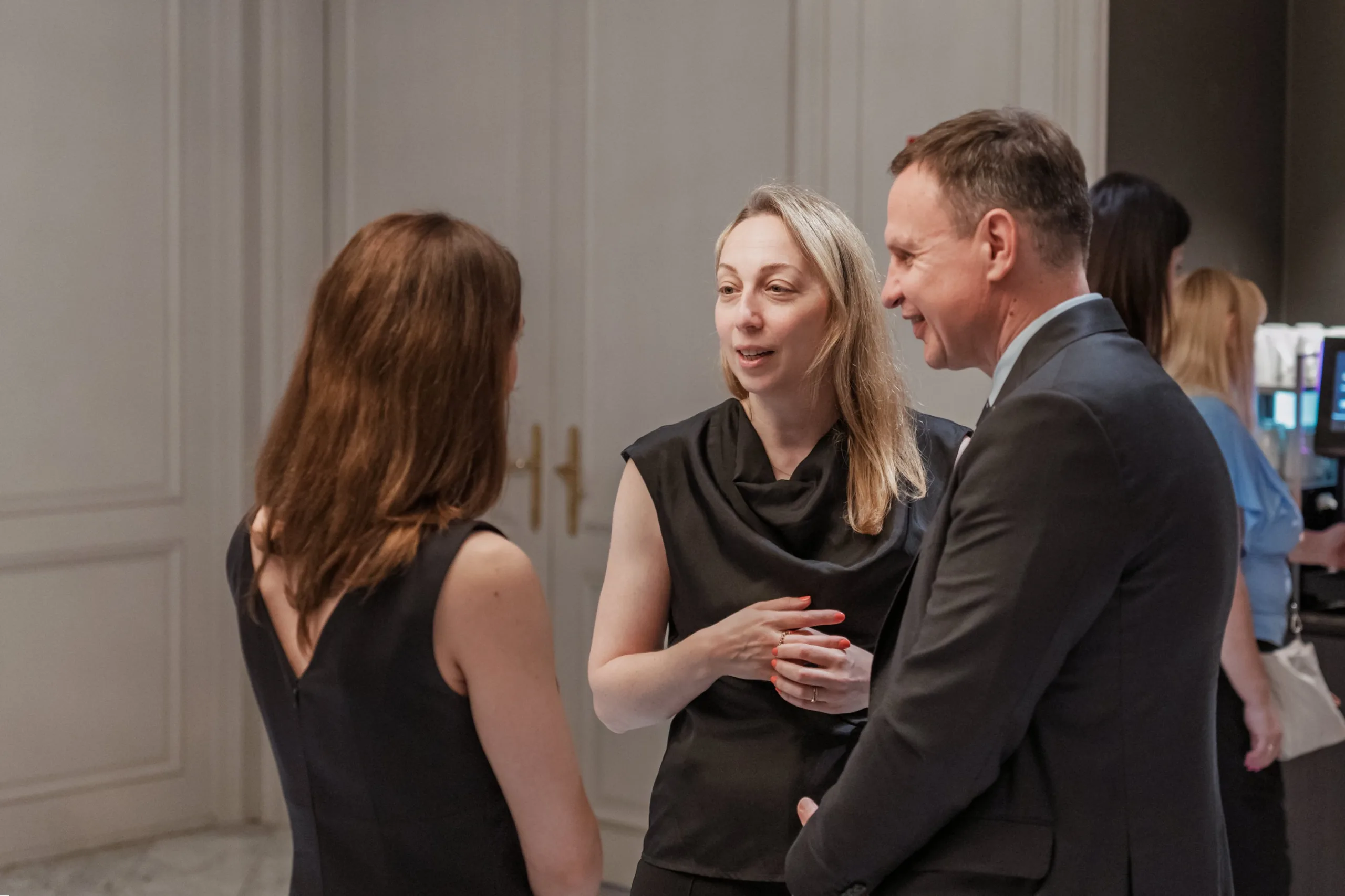 EU4Energy Conference Photography in Vienna Fedor Vasilev Photographer In Berlin Blonde woman in a black sleeveless top smiles while chatting with a man in a dark suit during a coffee break.