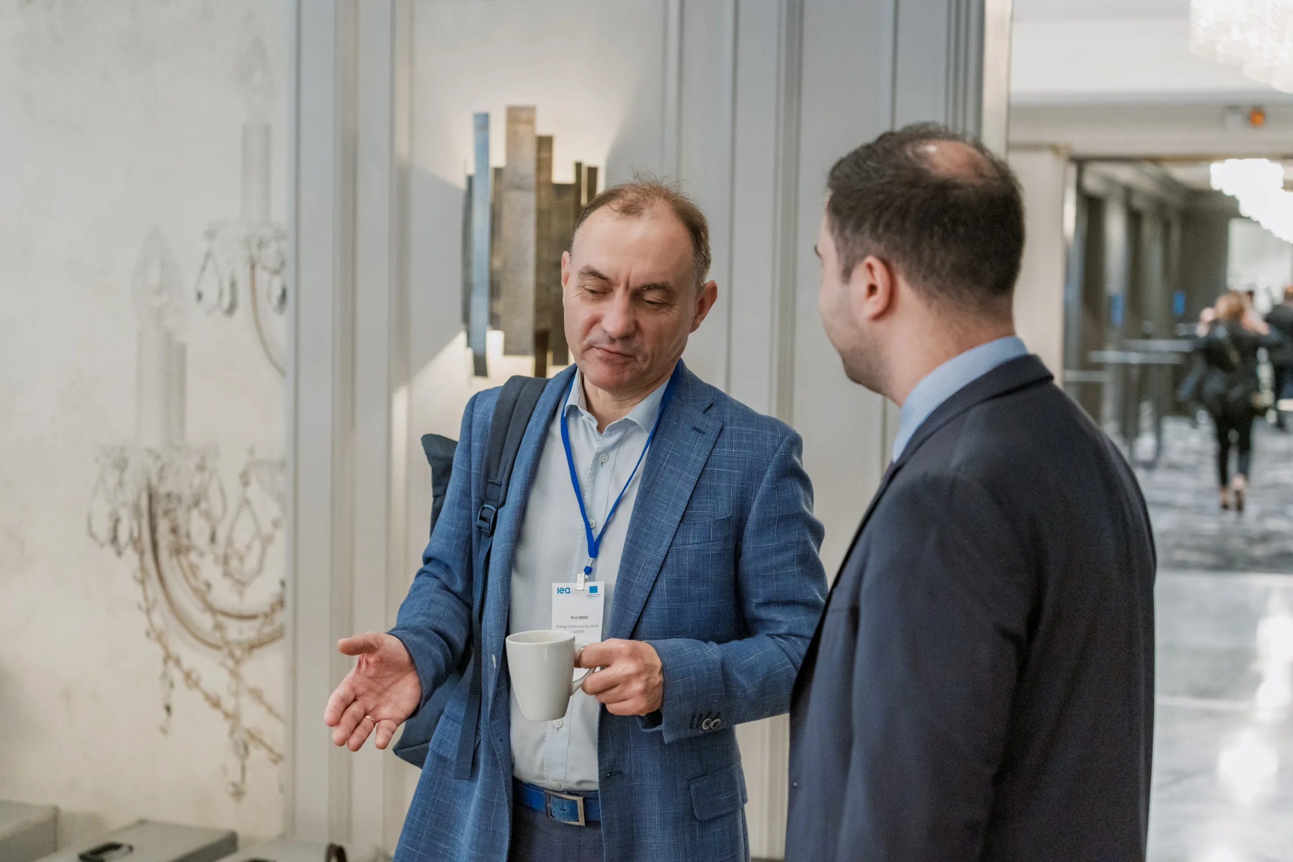 EU4Energy Conference Photography in Vienna Fedor Vasilev Photographer In Berlin Man in a blue blazer holding a coffee cup talks to a colleague at the EU4Energy conference.