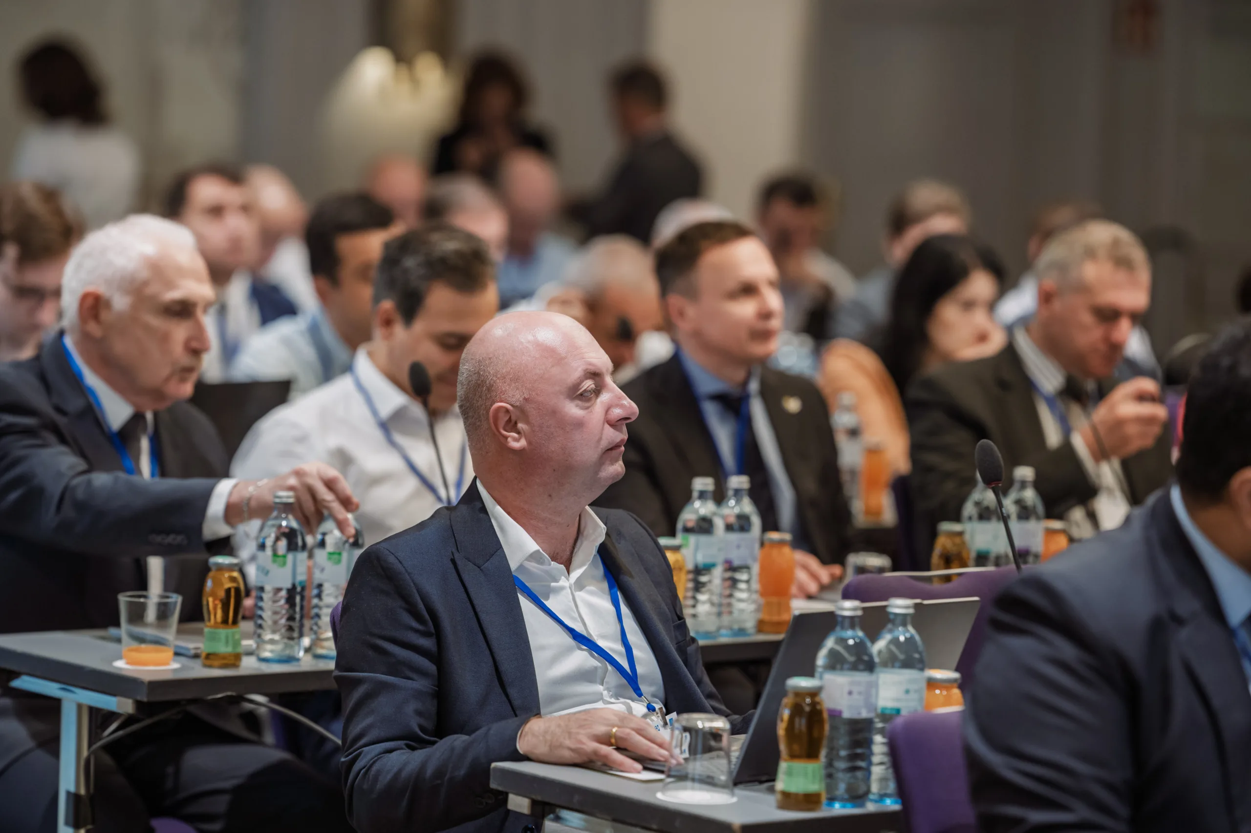 EU4Energy Conference Photography in Vienna Fedor Vasilev Photographer In Berlin Attendees in business attire sit at tables with laptops and water bottles during a professional conference in Berlin.