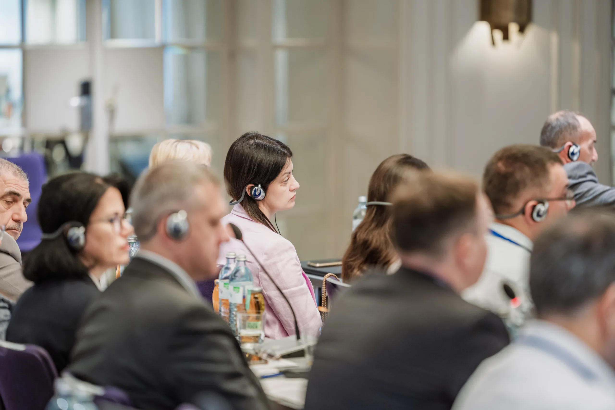 EU4Energy Conference Photography in Vienna Fedor Vasilev Photographer In Berlin Audience members wearing translation headsets listen intently while seated at desks during a formal event.
