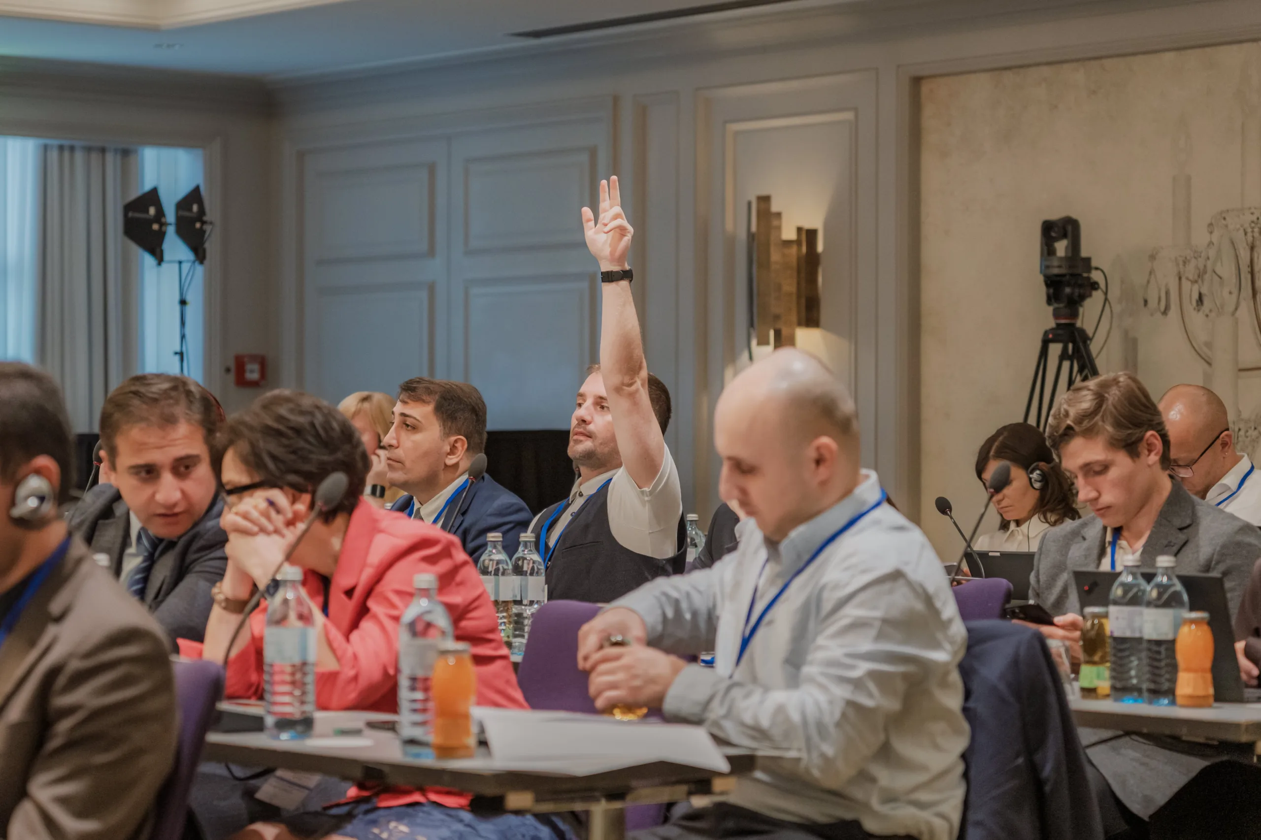 EU4Energy Conference Photography in Vienna Fedor Vasilev Photographer In Berlin Attendee with a raised hand participating in a Q&A session during an indoor corporate event.