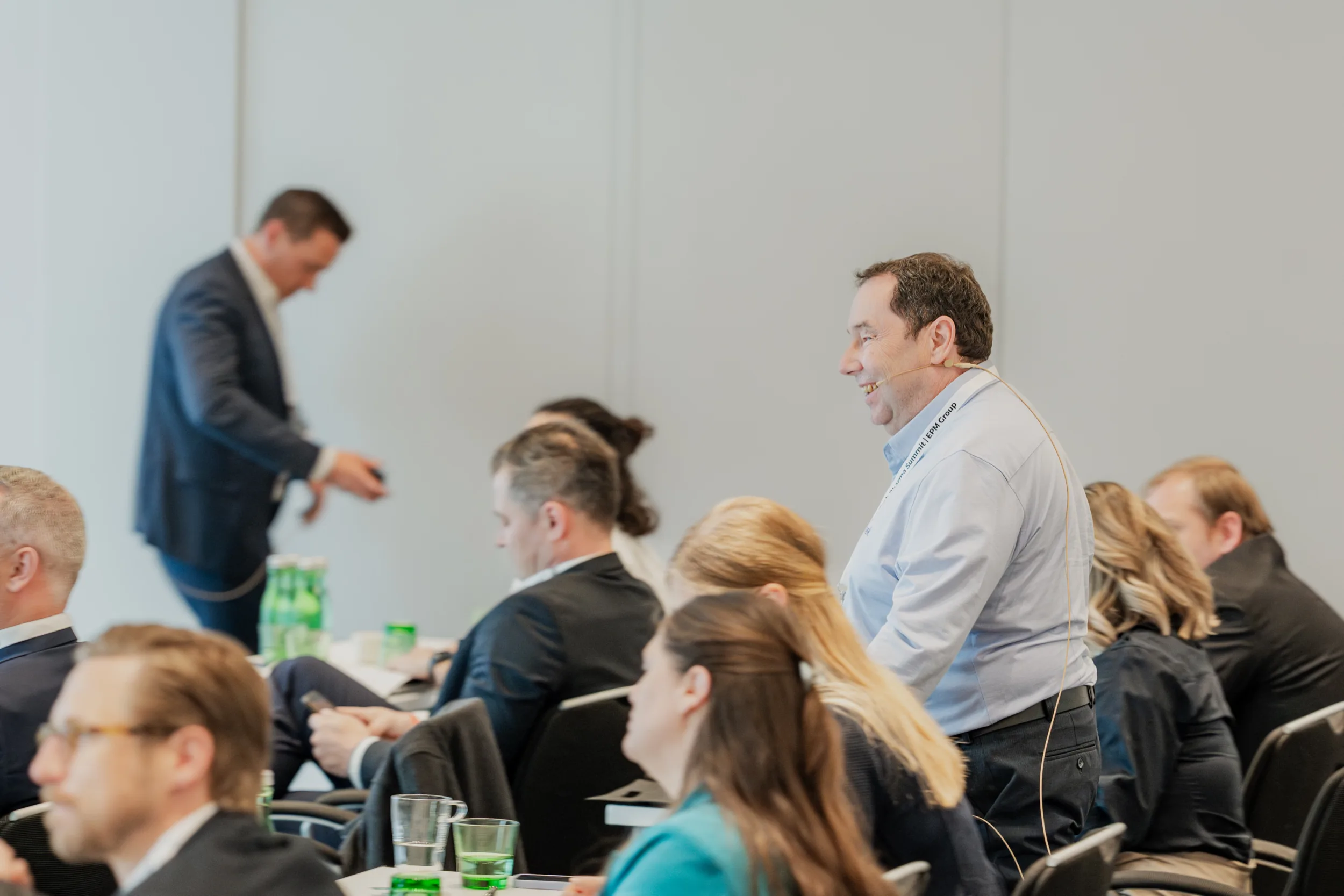Genup Summit | Medical Conference Photography and Product Expo Fedor Vasilev Photographer In Berlin Middle-aged man wearing a headset microphone stands to ask a question during a plenary session at the Genup Summit.